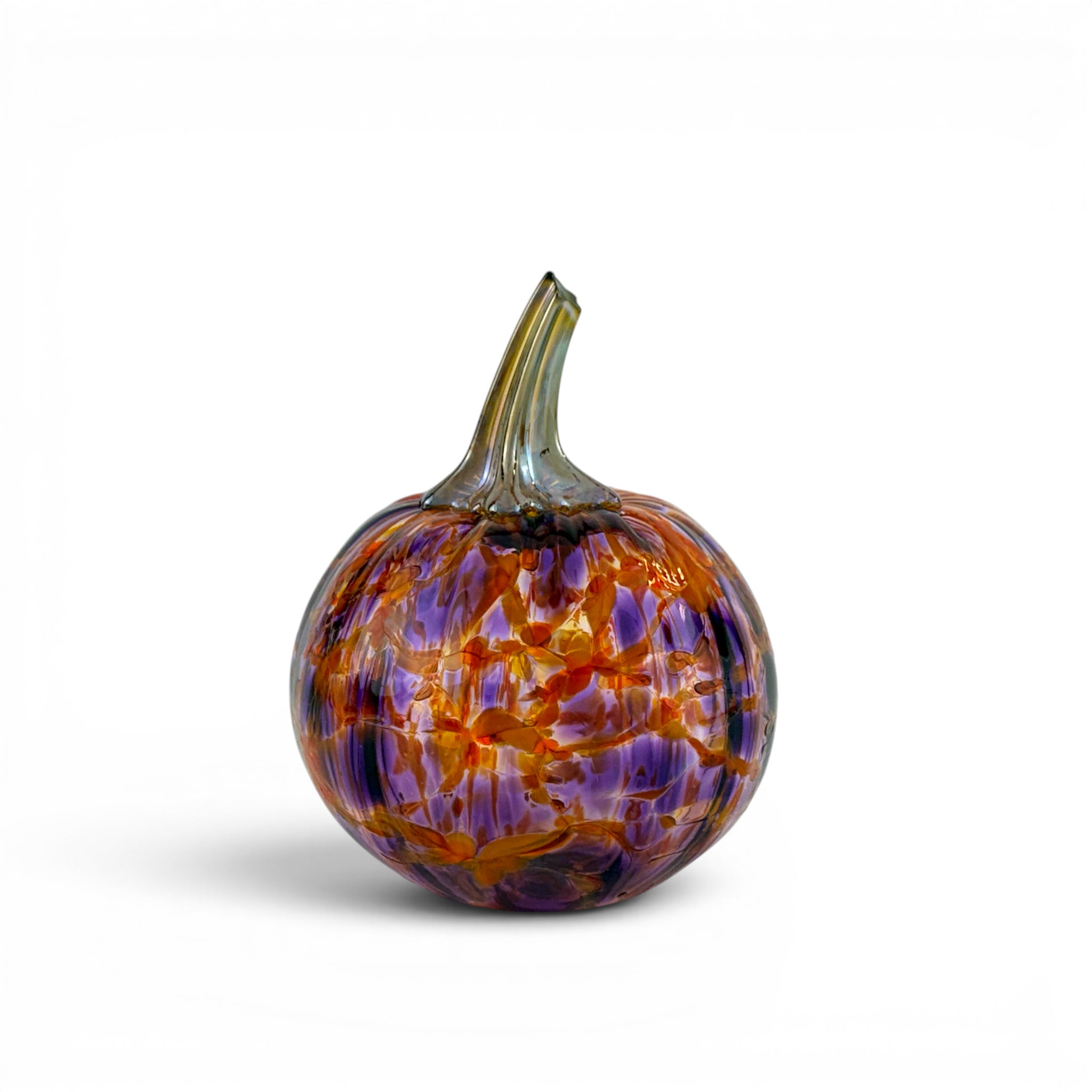 A decorative hand-blown glass pumpkin with a textured, marbled pattern of purple, orange, and yellow, featuring a realistic stem, set against a plain white background.