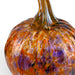 A close-up of a hand-blown glass pumpkin with a textured, marbled pattern of orange, amber, and purple colors on a white background.