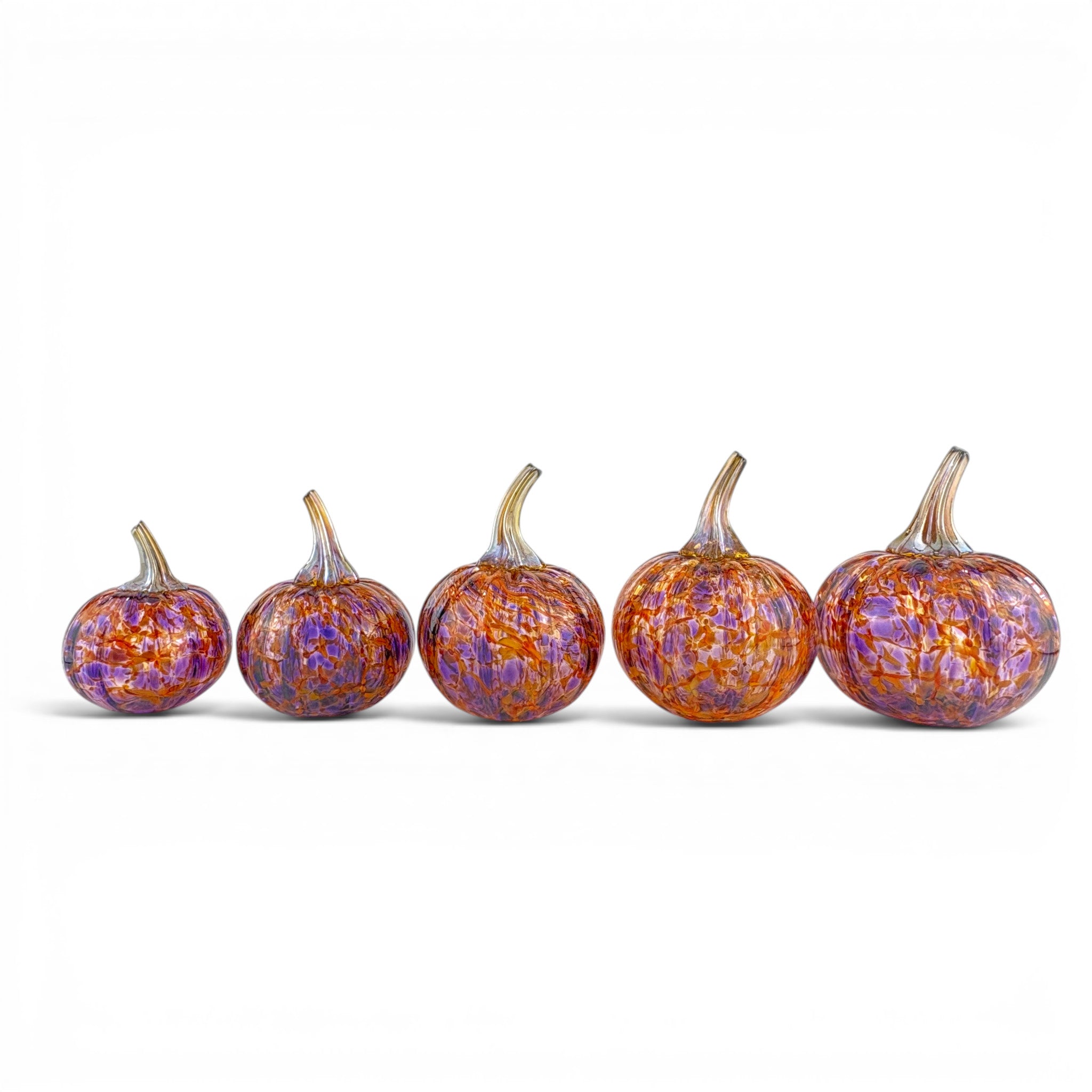 Five decorative glass pumpkins with textured, marbled orange, purple, and gold patterns, arranged in a row on a white background.