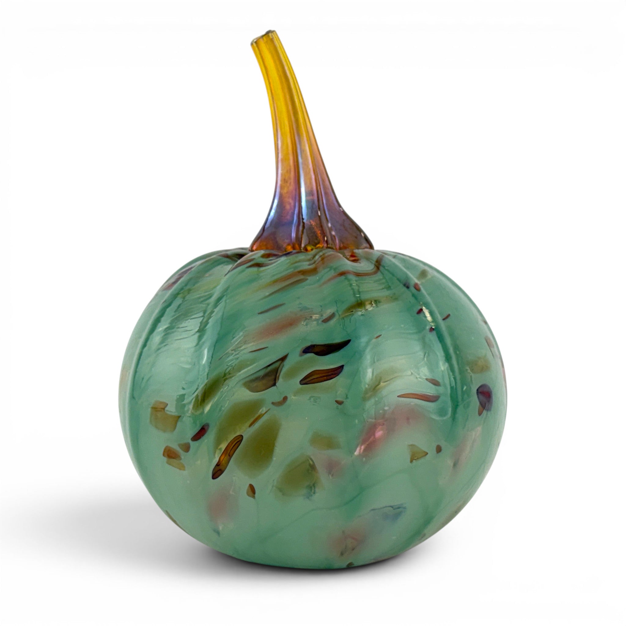 A hand-blown glass decorative pumpkin with a rounded body in translucent mint green and amber swirls, featuring a slender iridescent stem that transitions from yellow to purple, set against a plain white background.