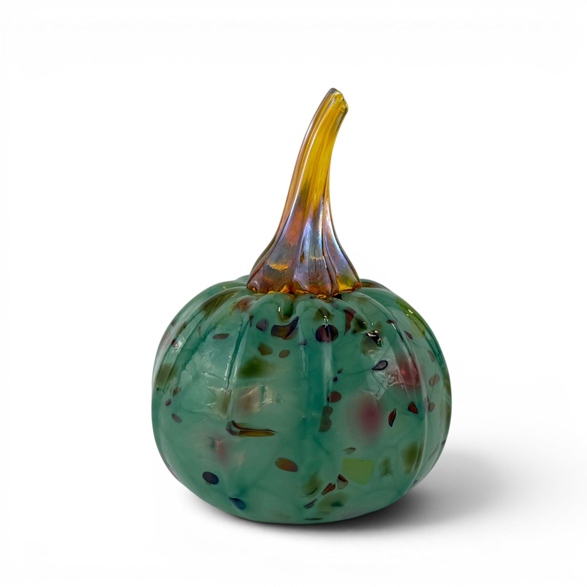 A hand-blown glass decorative pumpkin with a ribbed green body speckled with multicolored flecks and a curved amber-yellow stem, shown on a white background.