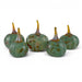Five decorative glass pumpkins in a speckled green and amber-brown style, arranged on a plain white studio background.