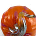 A close-up of a glossy orange glass pumpkin with purple marbling and a curved amber glass stem on a white background.