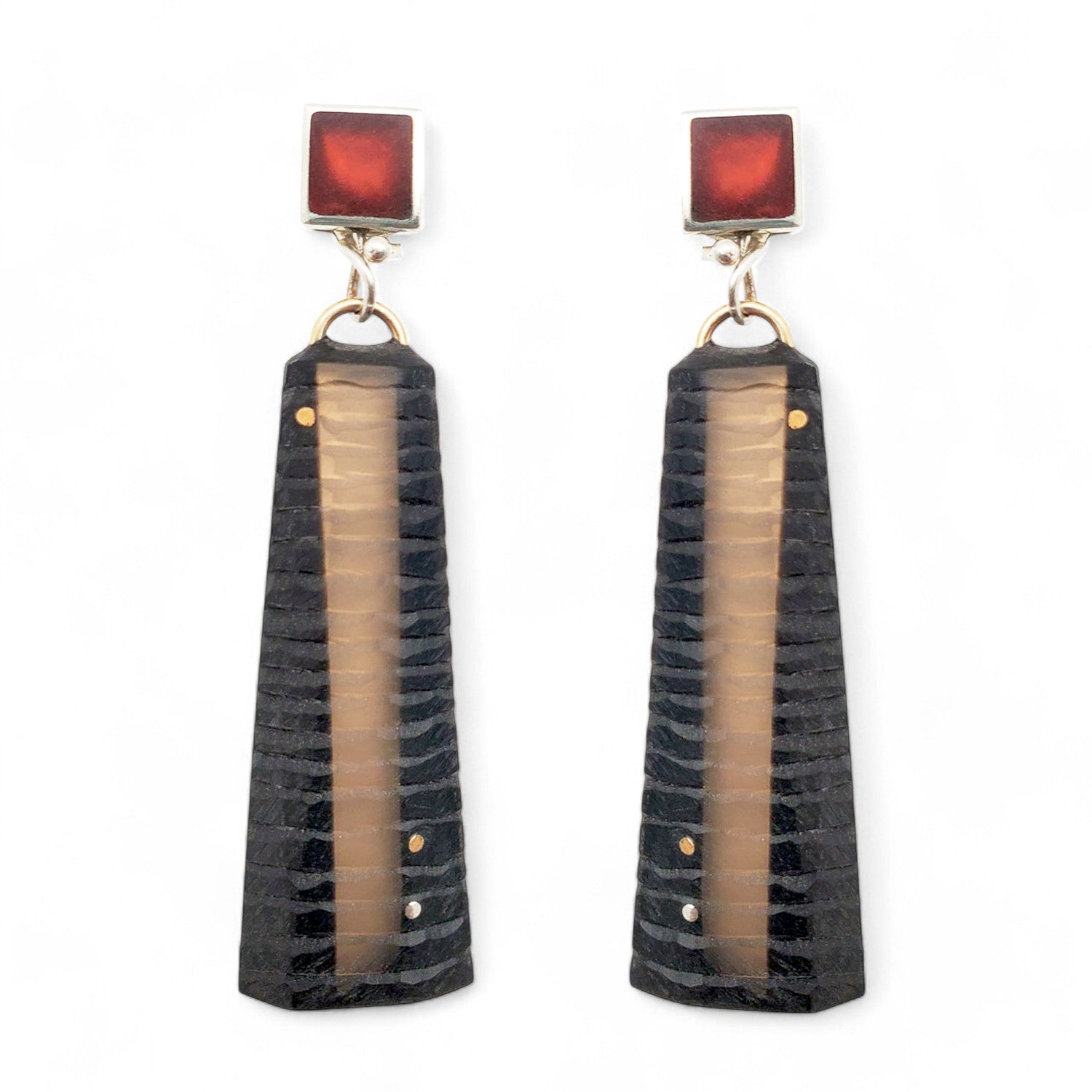 A pair of carved resin earrings with silver and gold color details, featuring a textured surface and trapezoidal shapes.