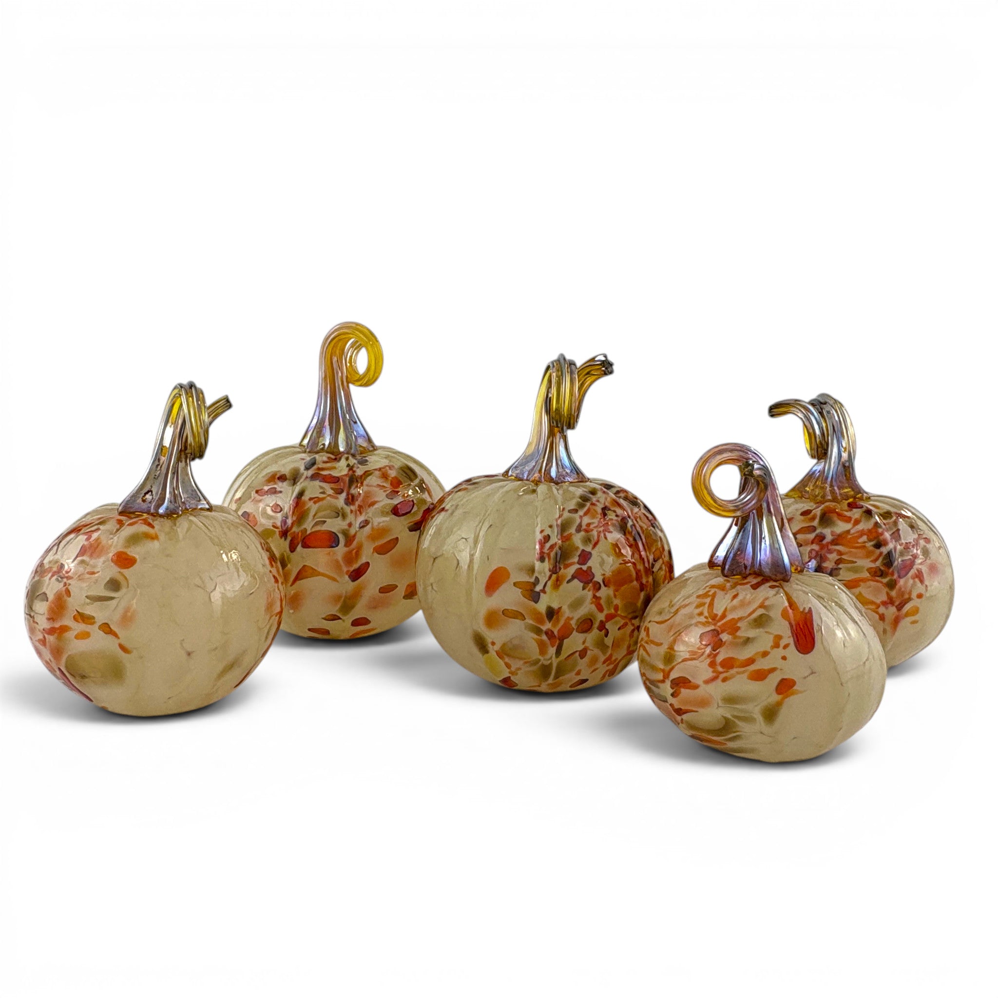 Five decorative glass pumpkins with amber and orange speckled bodies and metallic stems, arranged on a white studio background.