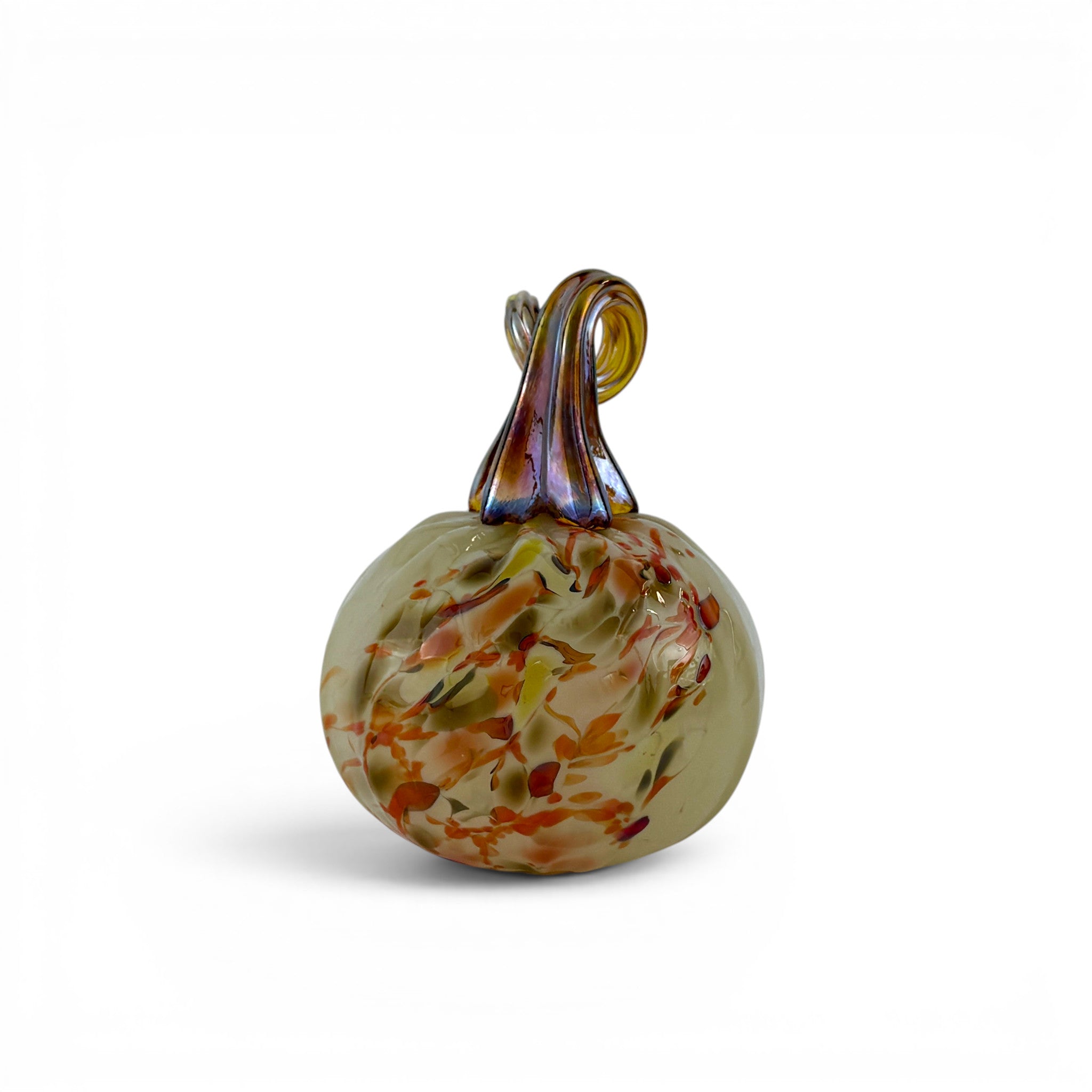 A hand-blown glass decorative pumpkin with a textured, speckled body in shades of beige, orange, and green, featuring a dark brown and amber glass stem, set against a plain white background.
