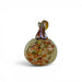 A hand-blown glass decorative pumpkin with a textured, speckled body in shades of beige, orange, and green, featuring a dark brown and amber glass stem, set against a plain white background.