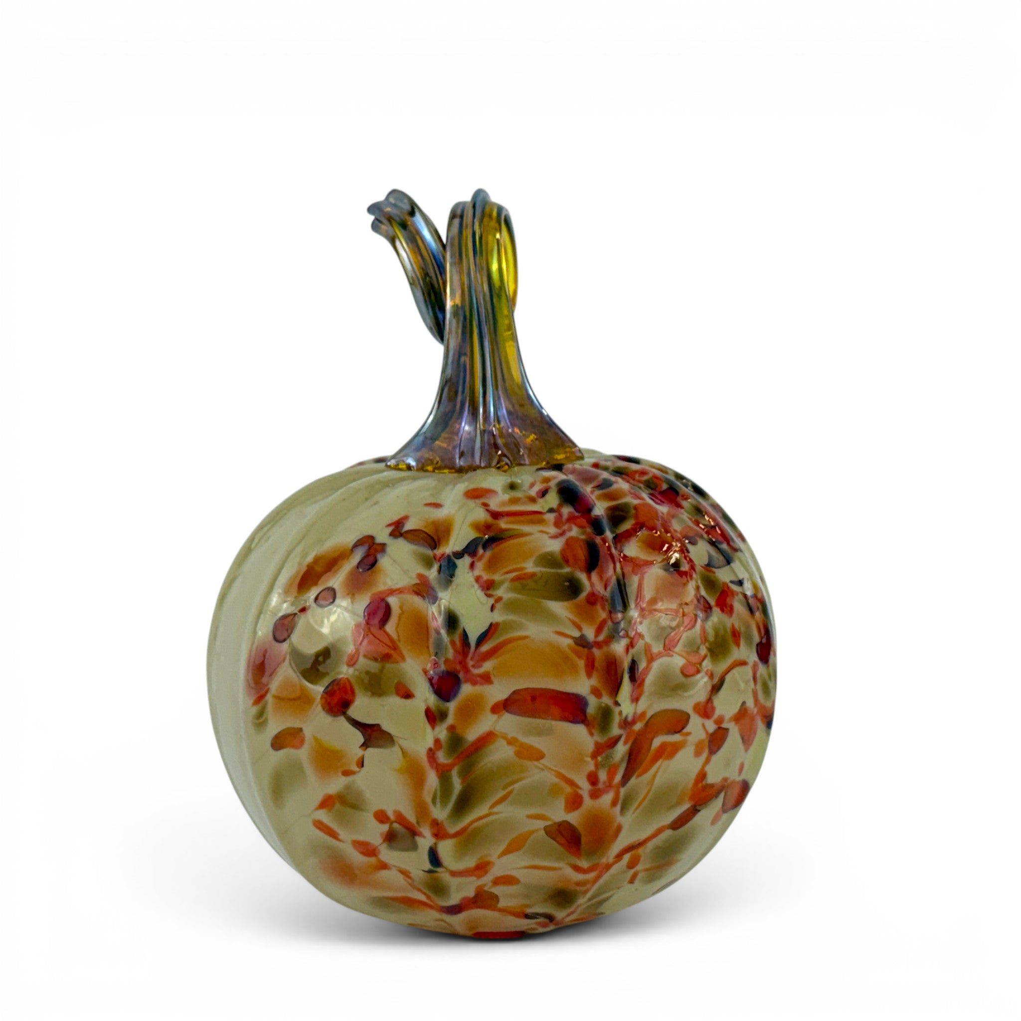 A hand-blown glass pumpkin sculpture with a ribbed bulbous body, featuring a mottled pattern of orange, red, green, and blue on a pale yellow-green base, with a twisted stem at the top, set against a plain white background.