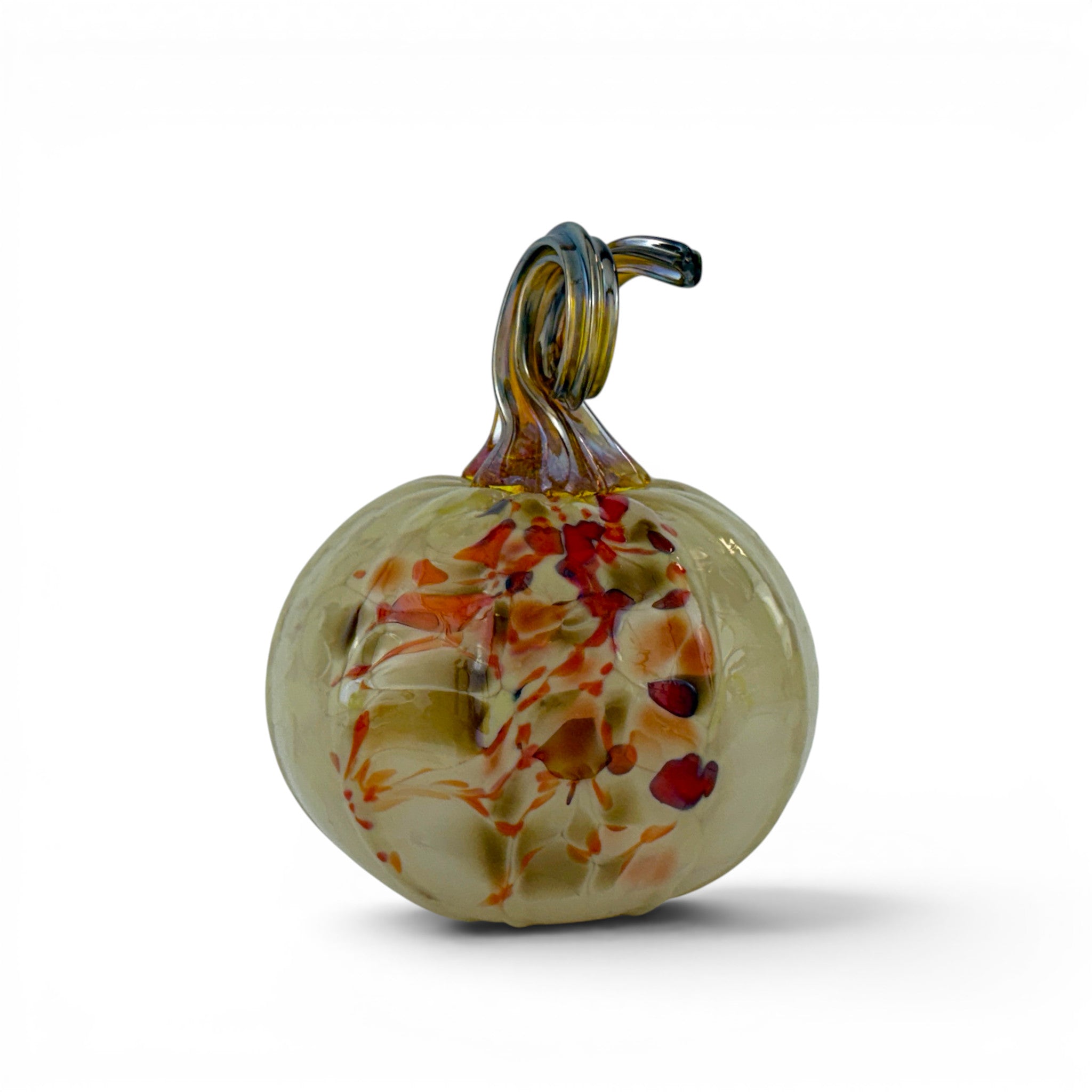 A hand-blown glass pumpkin figurine with a pale yellow-green base, decorated with orange, red, and brown marbled patterns, and featuring a dark brown stem, shown on a white background.