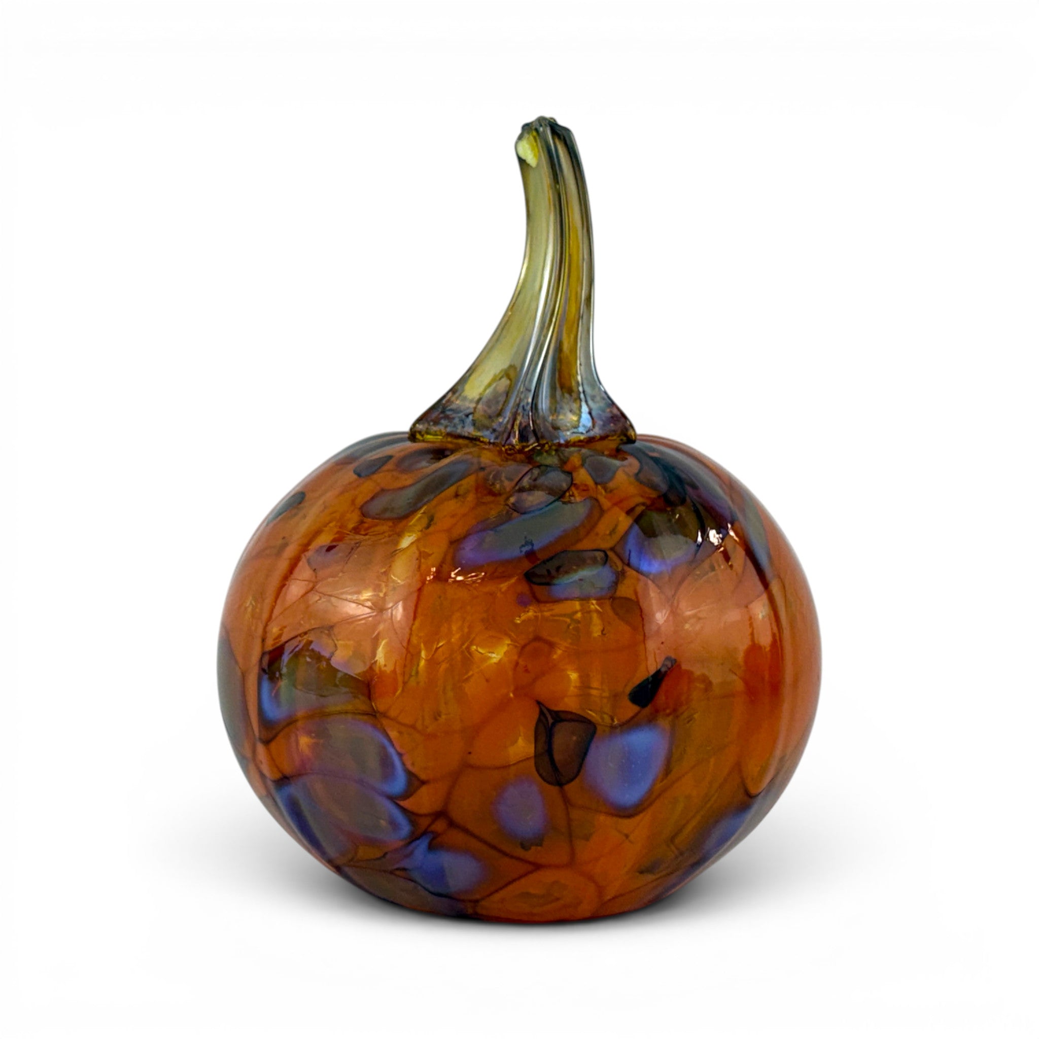 A hand-blown glass pumpkin with a rounded body in amber orange, featuring marbled swirls of blue, purple, and black, and a curved greenish-yellow stem, set against a plain white background.