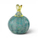 A hand-blown glass decorative object shaped like a rounded pear or pumpkin, featuring a textured blue-green body with a translucent yellow stem and looped top, set against a plain white background.