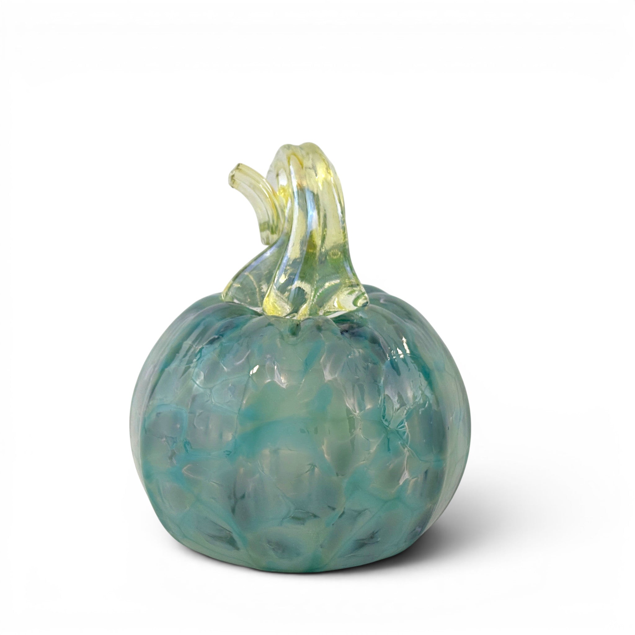 A decorative glass pumpkin figurine with a textured, marbled pattern in shades of teal, blue, and light green, featuring a translucent yellow-green stem, set against a plain white background.