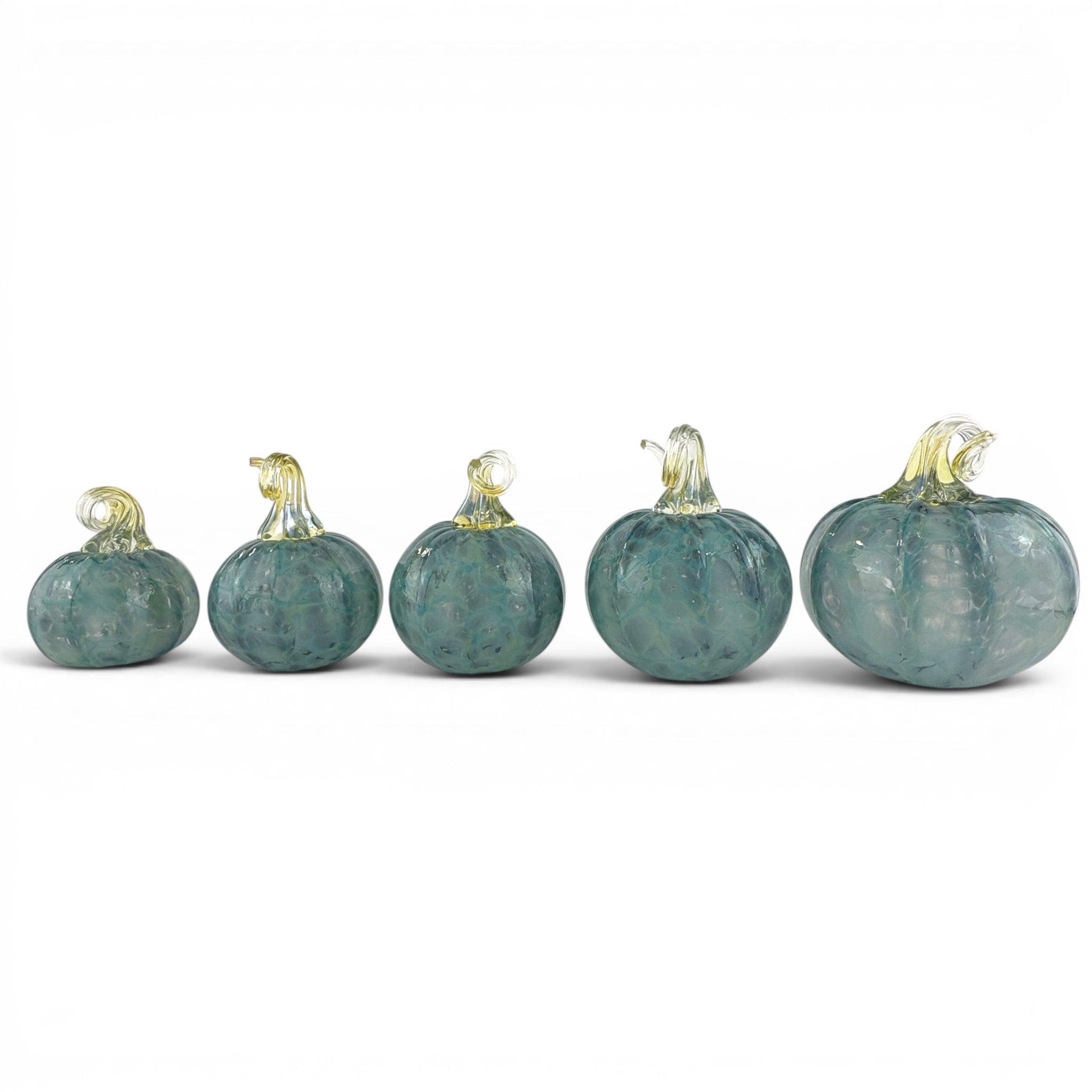Five small decorative glass pumpkins arranged in ascending size on a plain white background. The pumpkins are made of textured, marbled teal-blue glass with pale yellow stems.