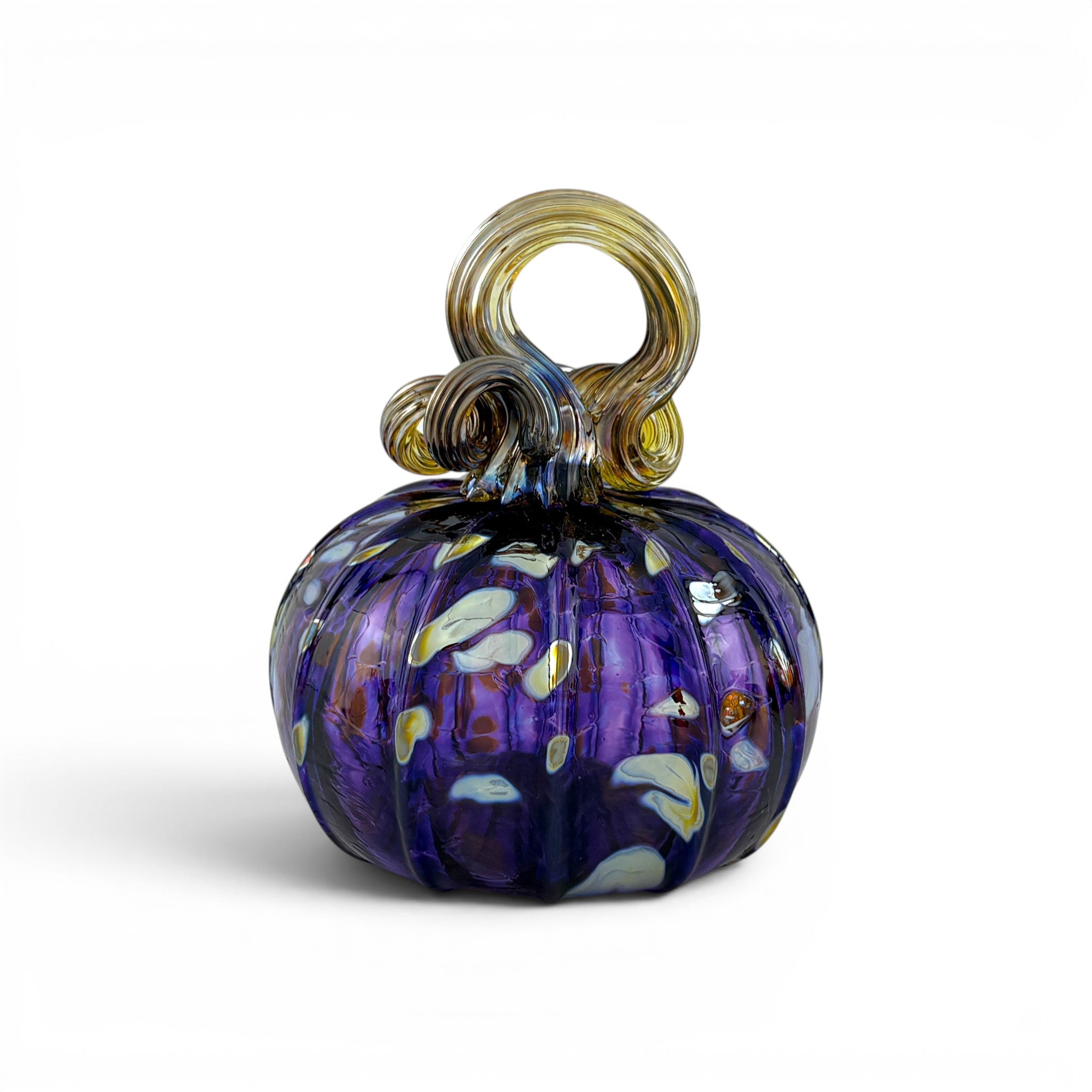 A hand-blown glass pumpkin with a deep purple body, white and yellow flecks, and a twisted amber-yellow stem.  