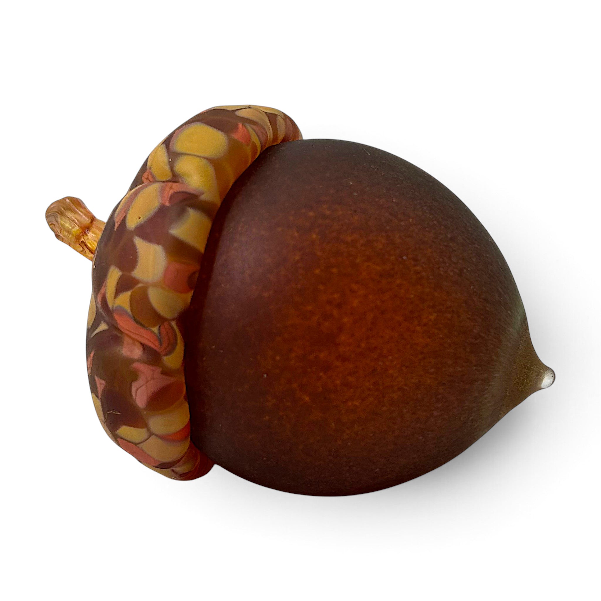 A decorative handcrafted glass acorn with a smooth dark brown body and a marbled cap in amber, orange, and brown tones.