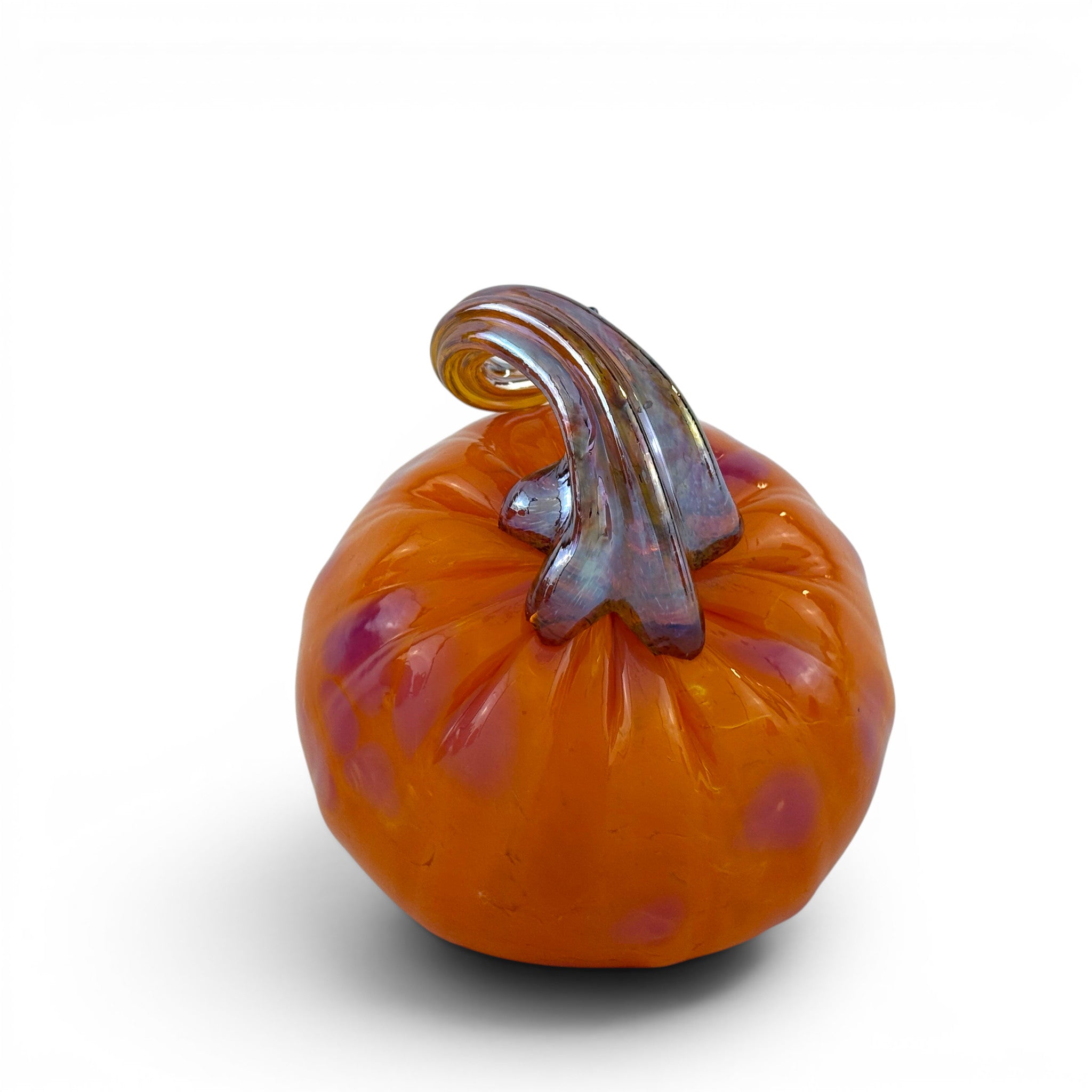 An orange glass pumpkin figurine with purple speckles and a textured, iridescent brown stem, shown on a white background with a soft shadow.
