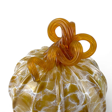 A decorative glass pumpkin with a textured, marbled golden-yellow body and a twisted, looped stem in a translucent amber-orange glass.