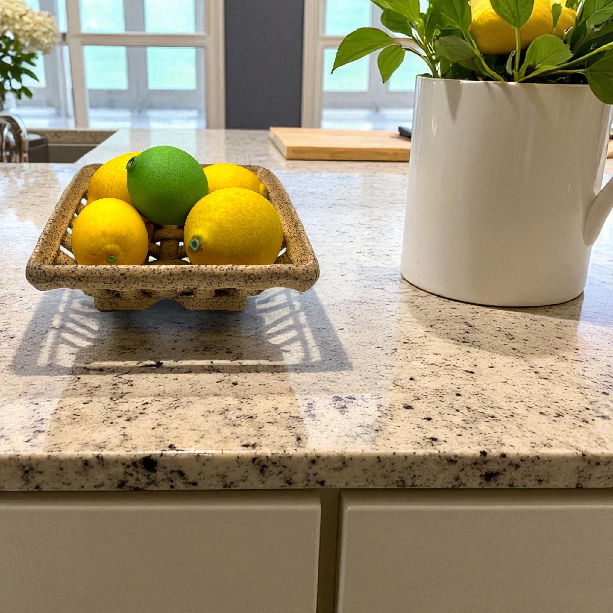 Lemons and a green lime in a small stoneware bowl on a kitchen countertop. North Carolina pottery at its finest! 