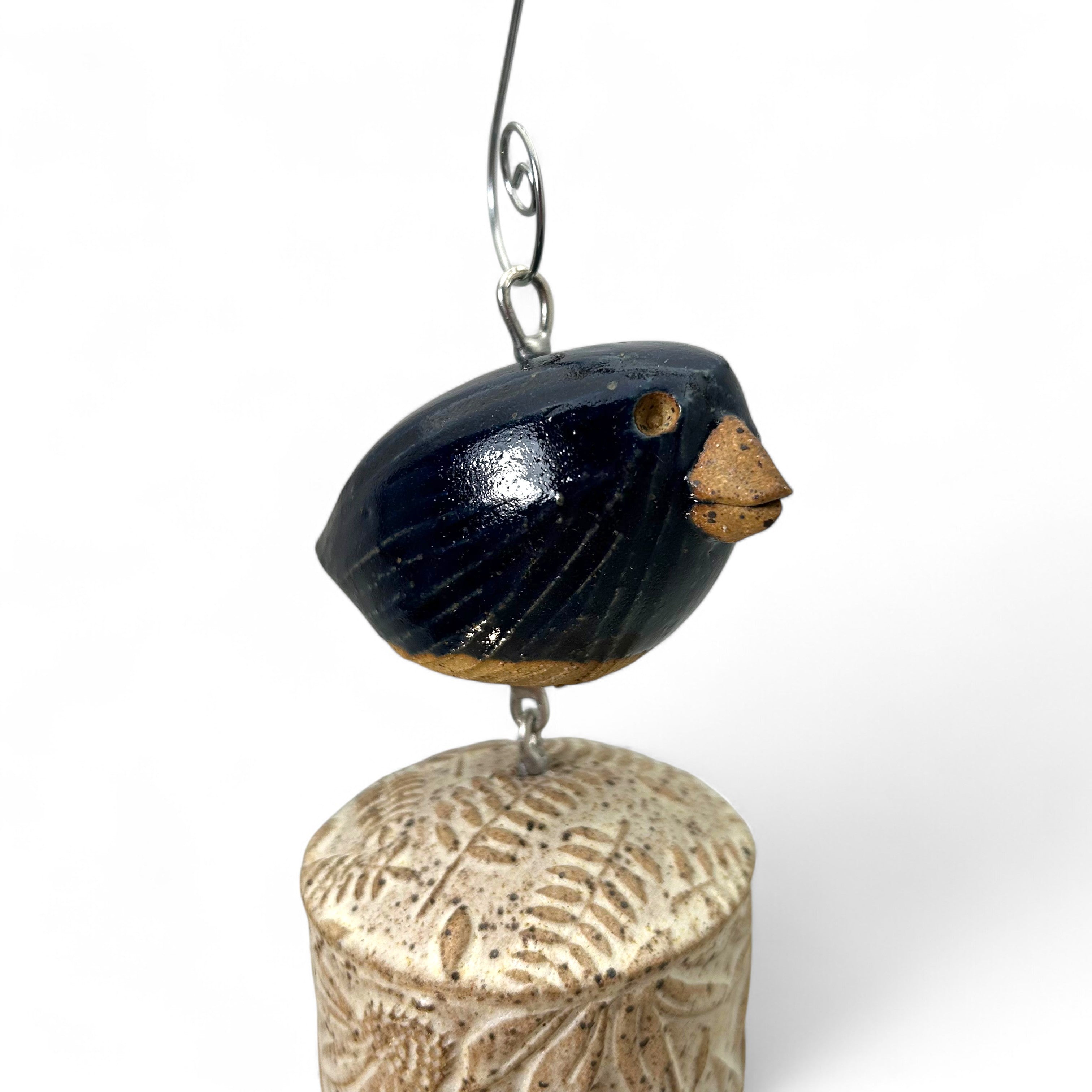 Decorative hanging ceramic bird bell ornament with a fern and cone flower design  