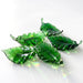 Five green translucent glass leaf sculptures with light reflections.