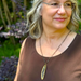 Woman wearing a brown top and necklace with a blurred natural background