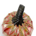 A handcrafted glass pumpkin with a glossy black ribbed stem, featuring marbled red, gold, and pink glass. 