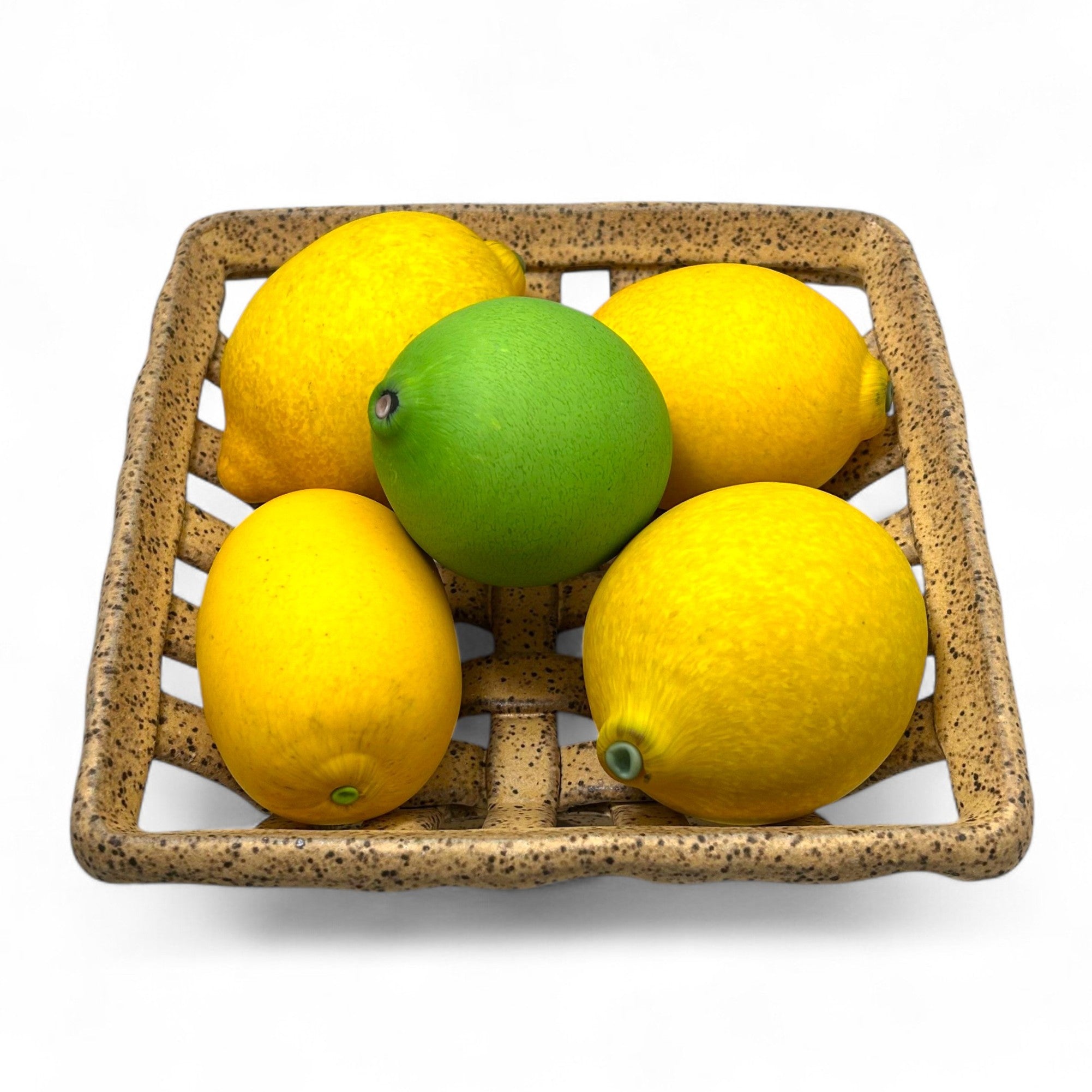 hand-blown glass lemons and lime displayed in a handwoven stoneware ceramic basket.