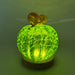 A glowing decorative pumpkin with a textured green cracked-glass sphere, a brown stem, displayed on and LED light with a round wooden base.    