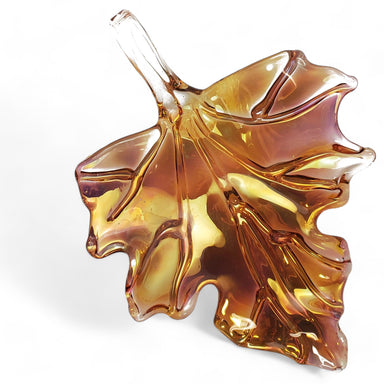 A glass sculpture of an amber leaf with a metallic sheen, designed for hanging or flat display.