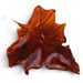 A translucent amber-brown glass ornament shaped like a maple leaf with a stem. 
