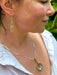 Close-up of a woman wearing gold and silver earrings and a silver necklace with  blue topaz gemstones.