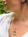 Close-up of a person wearing a silver and gold fill necklace with a blue topaz necklace.