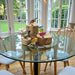 Decorative bird figurines on a glass table with a view of a garden.