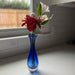 Blue vase with red and white flowers on a windowsill