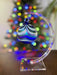 Decorative glass ornament on a stand with a Christmas tree in the background