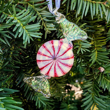 peppermint candy handmade glass ornament hanging on a holiday tree