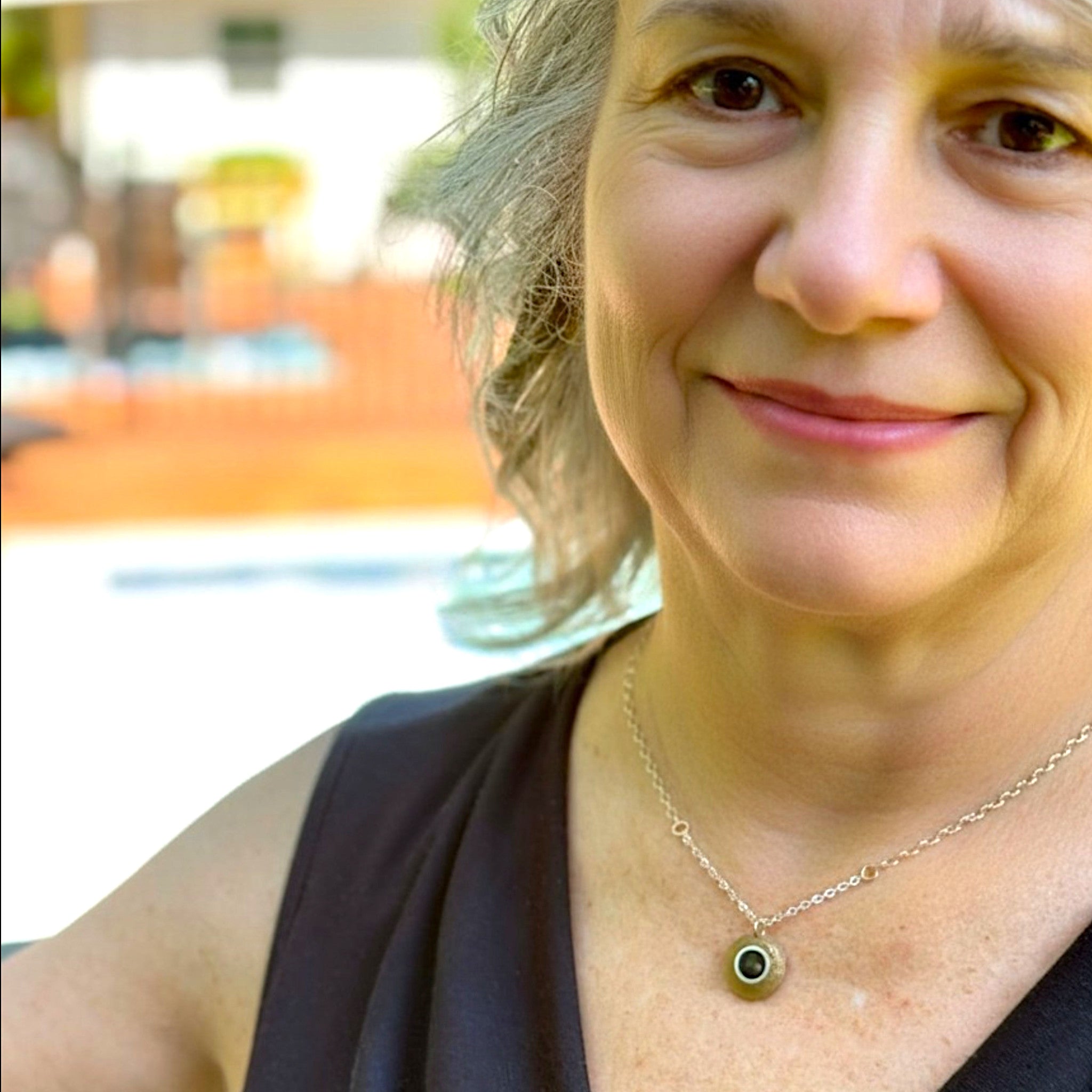 Woman with a necklace smiling outdoors