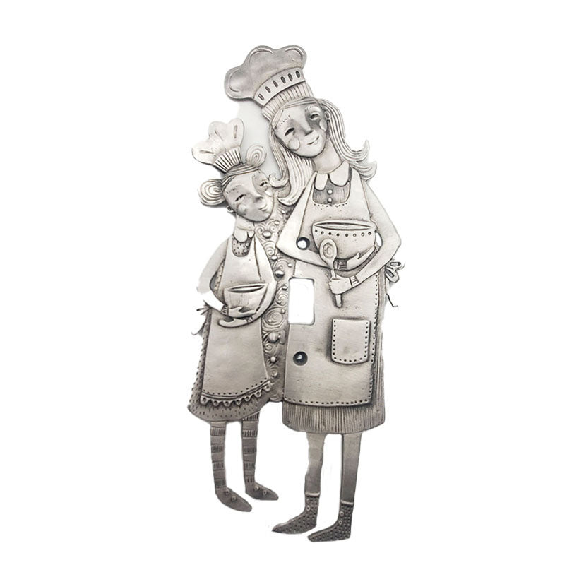 A pewter switch plate featuring an intricate design of a chef character with a smaller.