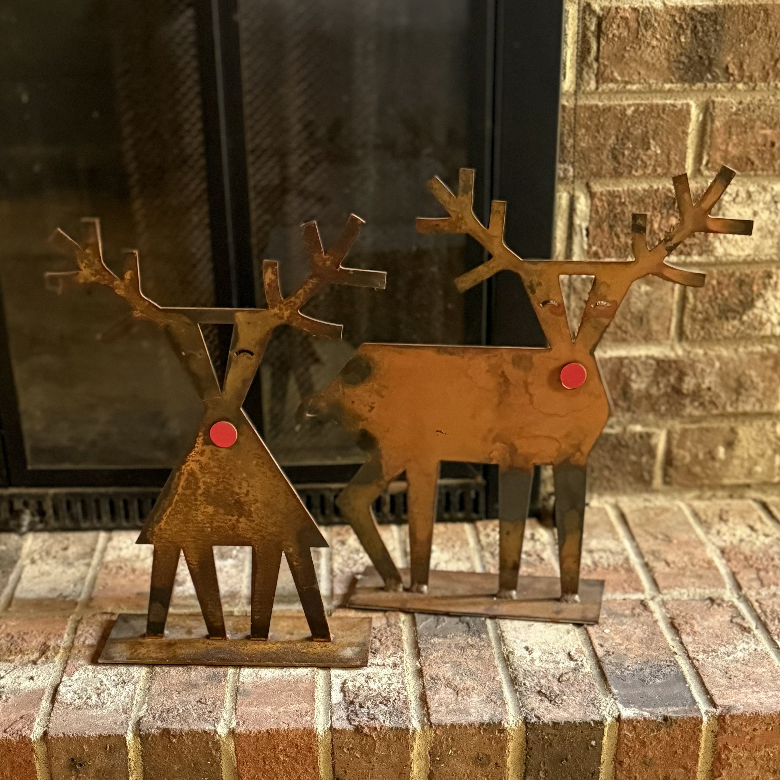 Metal reindeer decorations on a brick surface with a fireplace in the background