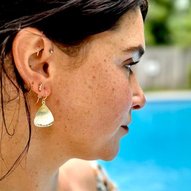 Close-up of a woman's profile with earrings, pool in the background