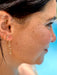 Close-up of a person wearing gold earrings with a blurred background