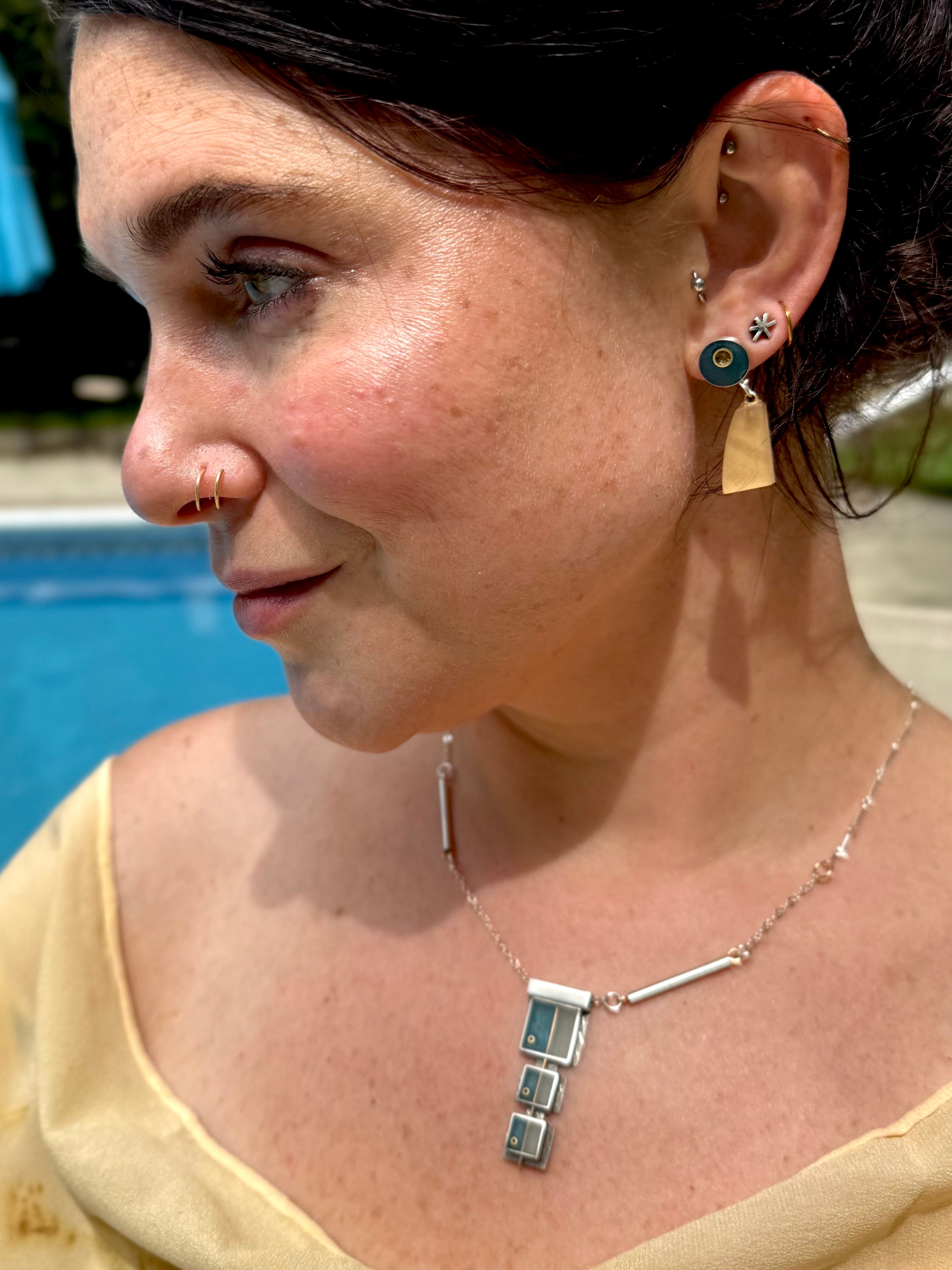 Close-up of a woman wearing earrings and a necklace with a blurred background