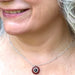 Close-up of a person wearing a silver necklace with a red pendant.