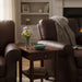 Cozy living room with brown leather chairs and a small table holding flowers and a bowl.