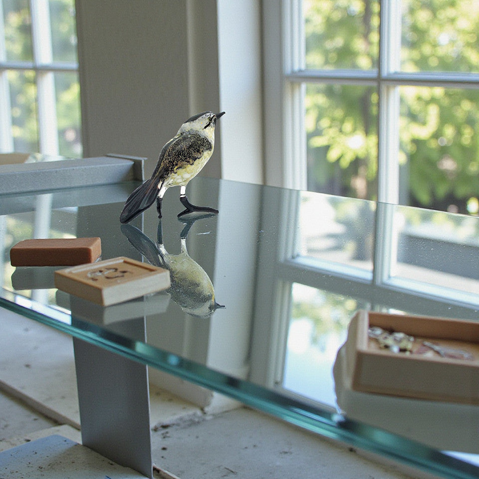 Handcrafted glass bird perched on a glass table brings nature indoors