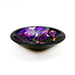 A handcrafted decorative glass bowl with a multicolored dichroic design, showing a mix of purple, black, and colorful pieces creating a visually intricate pattern.