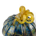 A close-up of a decorative glass pumpkin with a marbled blue and gold pattern and a twisted yellow stem.