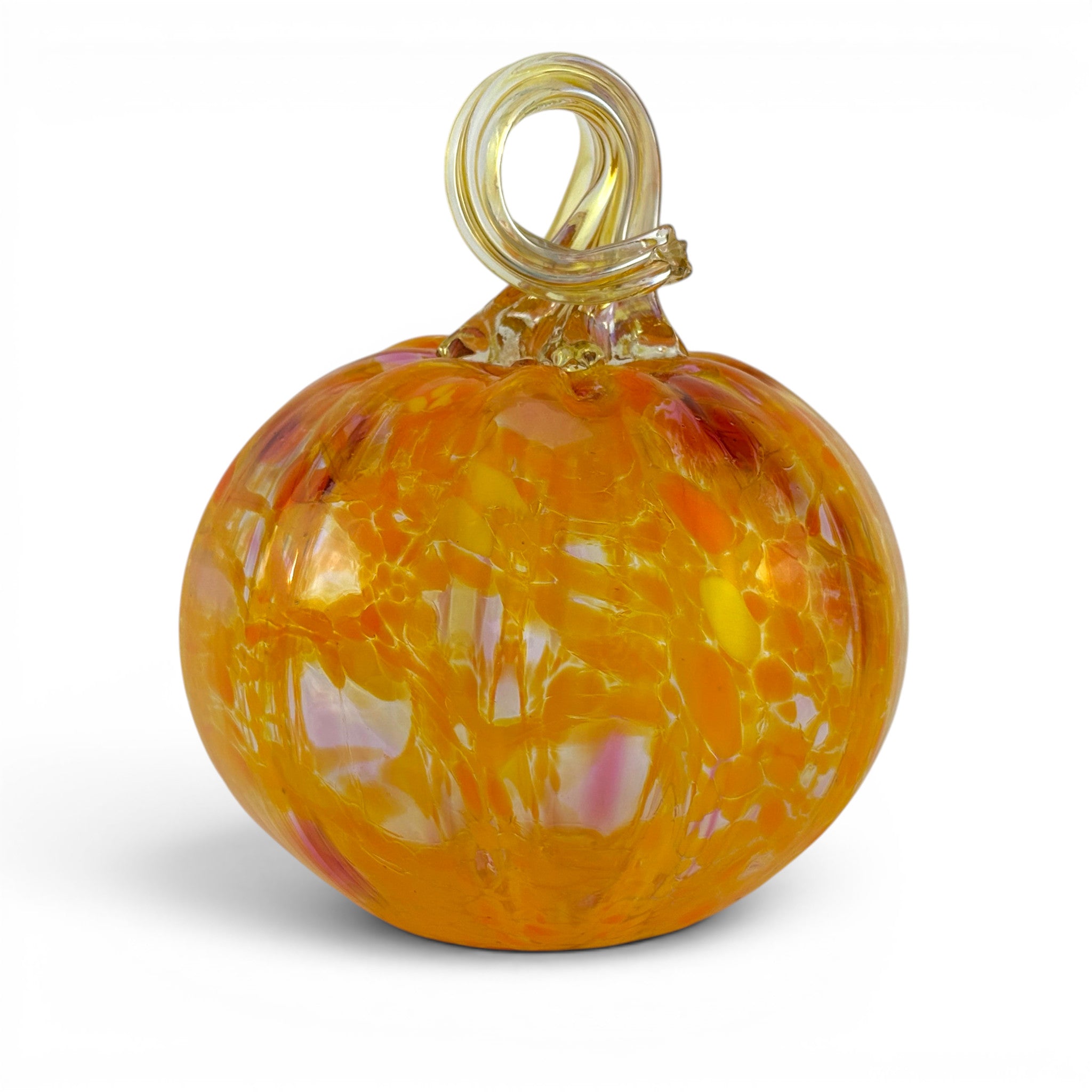 A hand-blown glass pumpkin ornament with a swirling pattern of orange, yellow, and pink, featuring a clear glass loop handle on a white background.