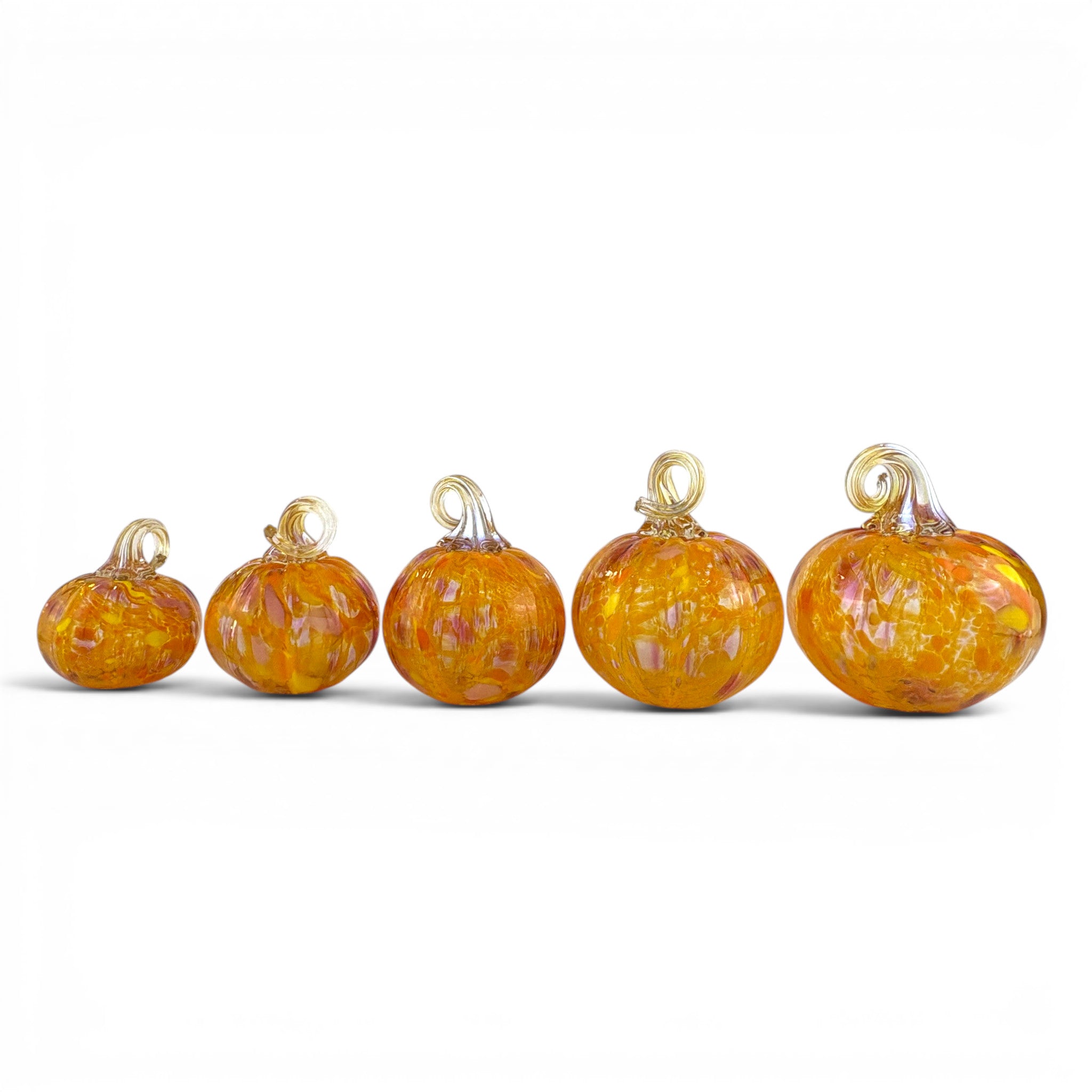 Five small orange glass pumpkins with gold-tone hanging loops, arranged in ascending size order on a white background.