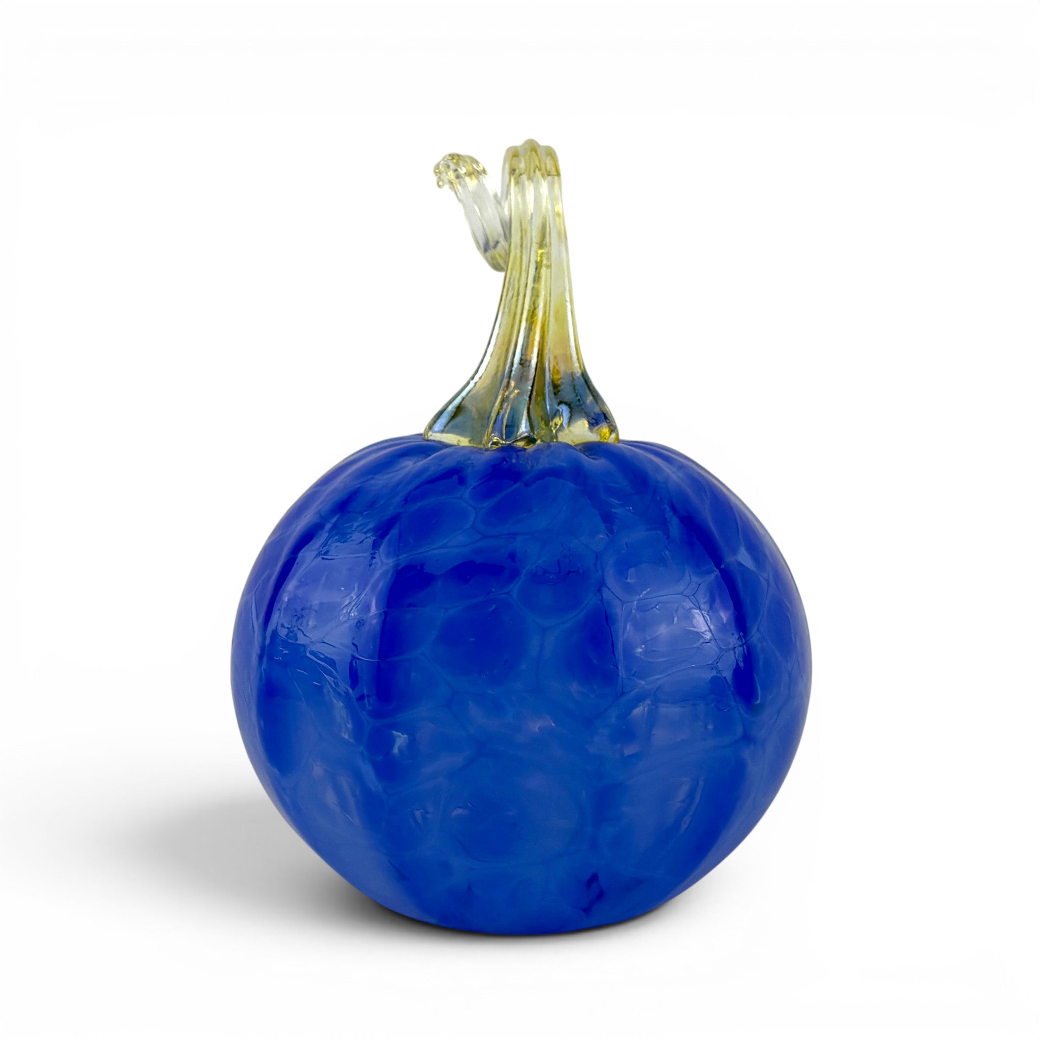 A decorative glass pumpkin sculpture with a textured cobalt blue body and a swirled stem in pale yellow and clear glass, shown on a white background.
